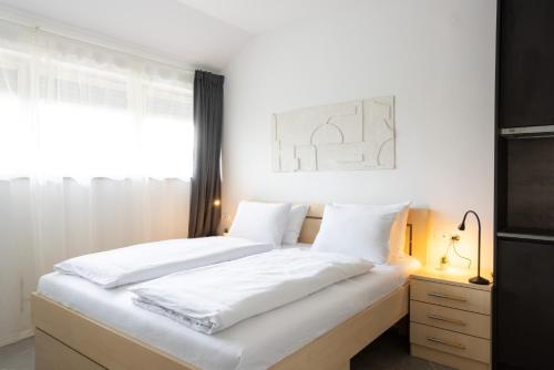1 dormitorio con 2 camas blancas y ventana en Apartments Trzin-Mlake w FREE Parking, en Trzin