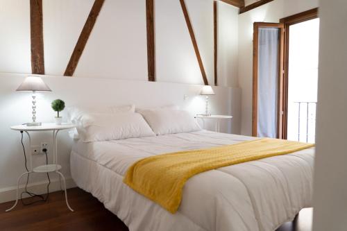 sypialnia z białym łóżkiem z żółtym kocem w obiekcie Tres Culturas Lux w mieście Toledo