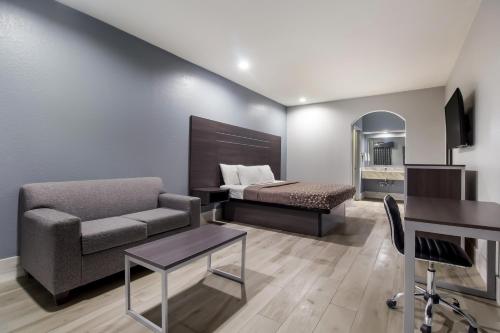 sala de estar con cama, sofá y escritorio en Americas Best Value Platinum Inn & Suites, en Houston