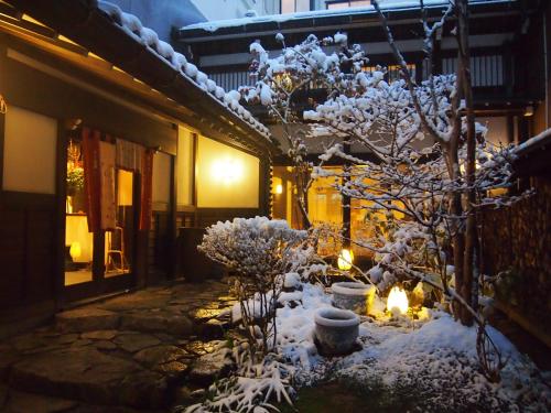 a tree covered in snow next to a building at Oyado Koto No Yume in Takayama