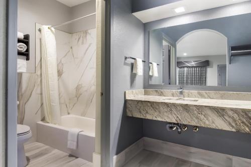 y baño con lavabo, bañera y aseo. en Americas Best Value Platinum Inn & Suites en Houston