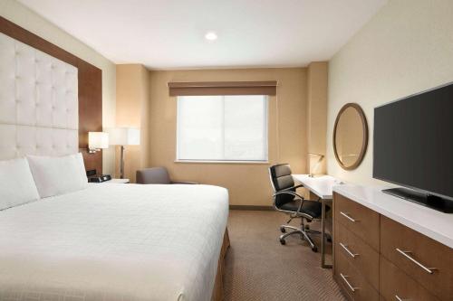 a hotel room with a bed and a desk and a television at Wyndham Anaheim in Anaheim