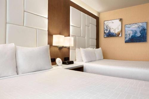 a hotel room with two beds with white pillows at Wyndham Anaheim in Anaheim