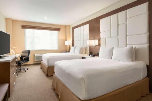 a hotel room with two beds and a television at Wyndham Anaheim in Anaheim