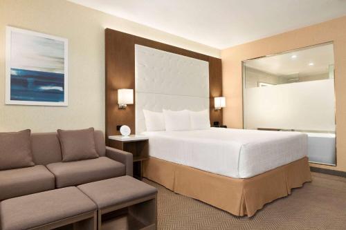 a hotel room with a large bed and a couch at Wyndham Anaheim in Anaheim