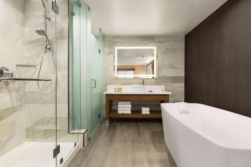 a bathroom with a bath tub and a sink at Wyndham Anaheim in Anaheim