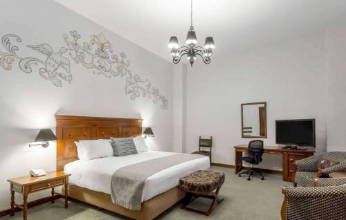 a bedroom with a bed and a desk and a television at Wyndham Costa del Sol Cusco in Cusco
