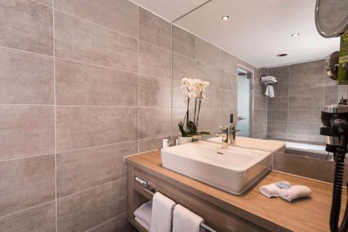 a bathroom with a sink and a mirror at Wyndham Grand Salzburg Conference Centre in Salzburg
