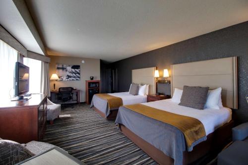 a hotel room with two beds and a flat screen tv at Best Western Harbour Pointe Lakefront in Saint Ignace
