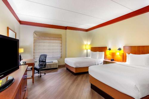 a hotel room with two beds and a desk and a tv at La Quinta by Wyndham Raleigh Crabtree in Raleigh