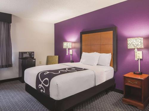 um quarto de hotel com uma cama grande e paredes roxas em Wingate by Wyndham Brunswick GA I-95 em Brunswick