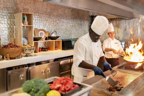 two chefs standing in a kitchen preparing food at Wyndham Grand Manama in Manama