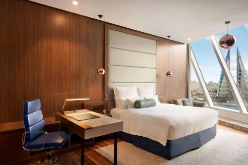 a bedroom with a bed and a desk and a window at Wyndham Grand Manama in Manama