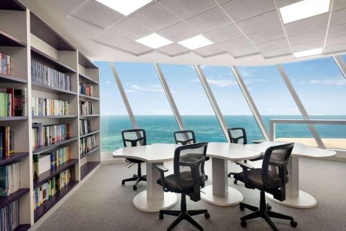 a library with a table and chairs and bookshelves at Wyndham Grand Manama in Manama