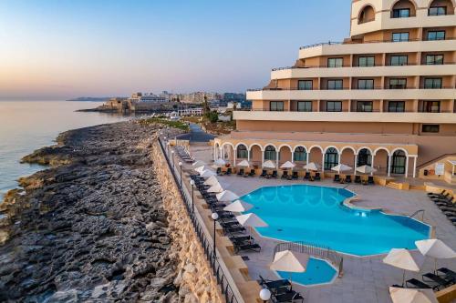 a beach with a large swimming pool and beach chairs at Radisson Blu Resort, Malta St. Julian's in St. Julianʼs