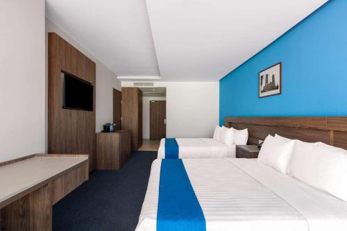a hotel room with two beds and a blue wall at Wyndham Puebla Angelopolis in Puebla