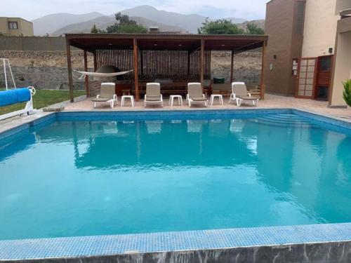 a large swimming pool with chairs and a gazebo at Cieneguilla Eco House in Cieneguilla
