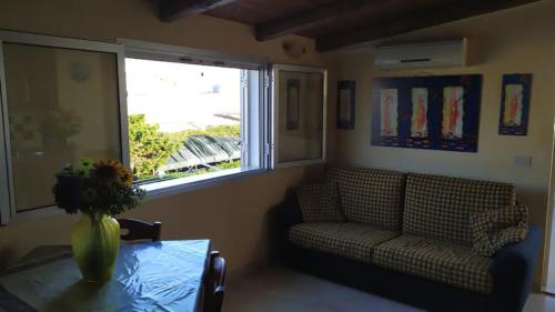 een woonkamer met een bank, een tafel en een raam bij Veranda Nasca in Donnalucata