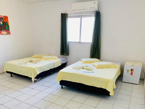 two beds in a room with a window at Pousada Beira Mar in Pitimbu