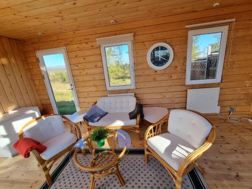 um quarto com cadeiras, uma mesa e janelas em Adventure Eagle Cottege em Geysir