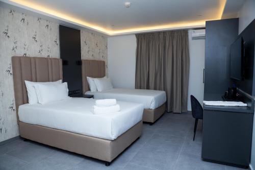 a hotel room with two beds and a television at INCANTO RESIDENCIAL in Maputo