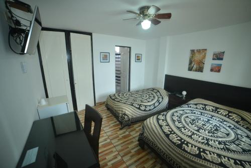 Cette chambre comprend deux lits et un ventilateur de plafond. dans l'établissement Residencial Carlos, à Lima
