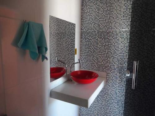 La salle de bains est pourvue de 2 lavabos rouges et d'un miroir. dans l'établissement Pousada & Restaurante do Vaninho, à Januária