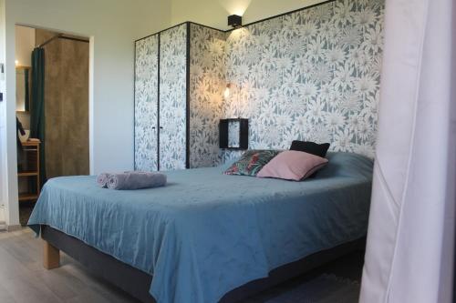 a bedroom with a blue bed with pink pillows at Lodges Mont-Vert in Le Robert