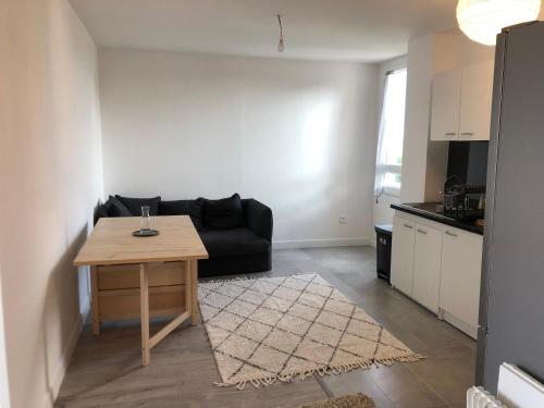 un salon avec un canapé noir et une table dans l'établissement Evry Time, Évry-Courcouronnes