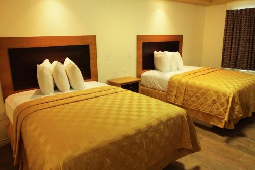 a hotel room with two beds with white pillows at Maverick Inn in Eagle Pass