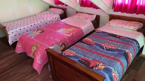 Habitación con 2 camas individuales y sábanas rosas. en Casa El Descanso en San Antonio de Arredondo