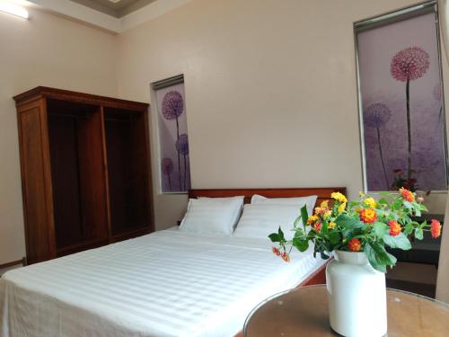 a bedroom with a bed and a vase of flowers on a table at GiaBinh Homestay in Cao Bằng