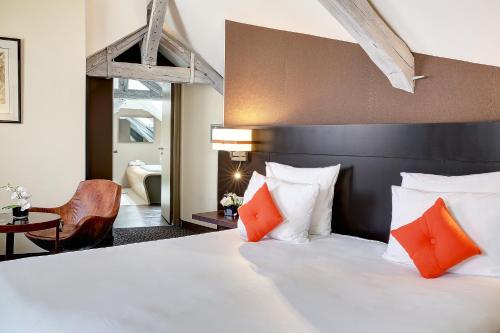 a bedroom with a large white bed with orange pillows at Best Western Premier de La Poste & Spa in Troyes