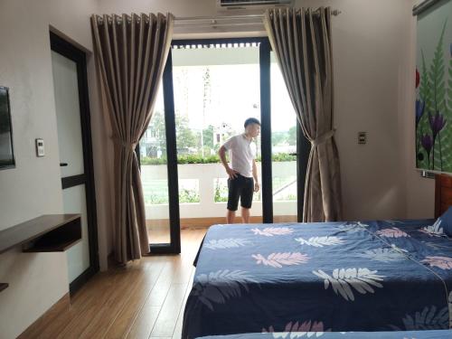 a man standing in a bedroom looking out the window at GiaBinh Homestay in Cao Bằng