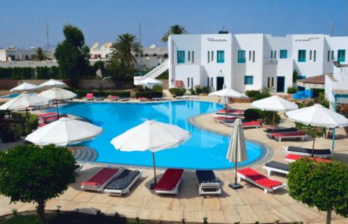 ein großer Pool mit Stühlen und Sonnenschirmen in der Unterkunft Sunset Hotel sharm El Sheikh in Sharm El Sheikh