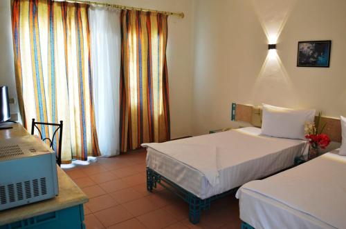 Habitación de hotel con 2 camas y escritorio con ordenador en Sunset Hotel sharm El Sheikh en Sharm El Sheikh