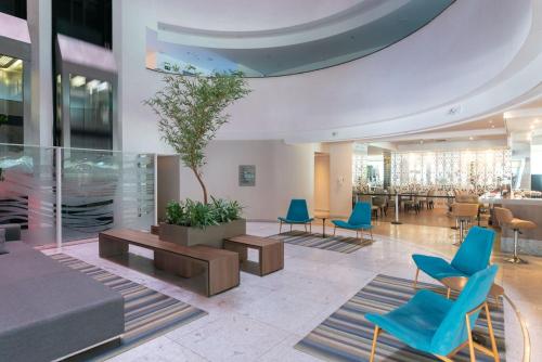 a lobby with blue chairs and a table at Apartamento em Hotel Beira Mar de Boa Viagem in Recife