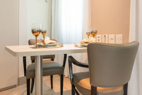 a table with two glasses of wine and two chairs at Apartamento em Hotel Beira Mar de Boa Viagem in Recife