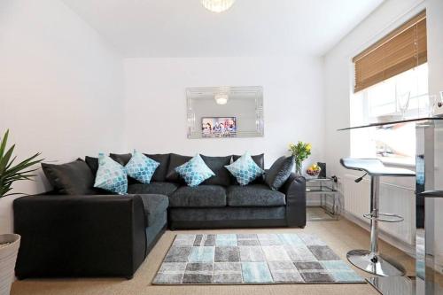 sala de estar con sofá negro y almohadas azules en Stafford Rest Ginger & Gold Ltd en Norwich
