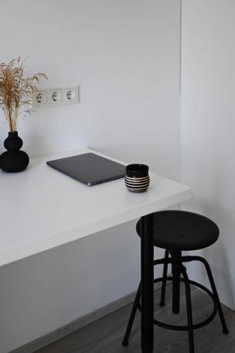 a white desk with a laptop and a black stool at ÁLka - Cozy Room by the Sea With Private Hot Tub in Njarðvík