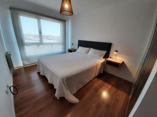 een slaapkamer met een wit bed en een groot raam bij Departamentos DSM in Necochea