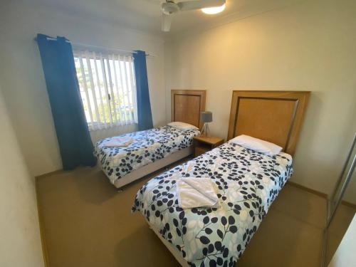 a bedroom with two beds and a window with blue curtains at Unit 46 Seafront Estate in Jurien Bay