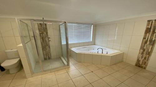 a bathroom with a shower and a tub and a toilet at The Beach House in Jurien Bay