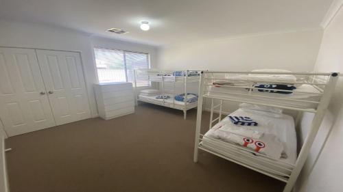 a room with three bunk beds and a window at Maniki Gardens in Jurien Bay
