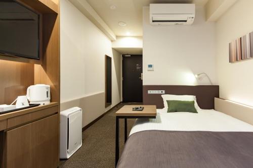 a hotel room with a bed and a tv at Y's HOTEL Hanshin Amagasaki Ekimae in Amagasaki