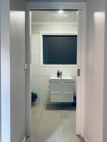 baño con lavabo blanco y TV en Yours and Theirs Pet Friendly Accommodation, en Myrtleford