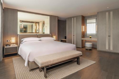 a bedroom with a large white bed and a mirror at Intercontinental Shenzhen Dameisha Resort by IHG in Shenzhen