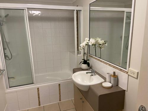 a white bathroom with a sink and a bath tub at Lakeside Central Apartment in Townsville