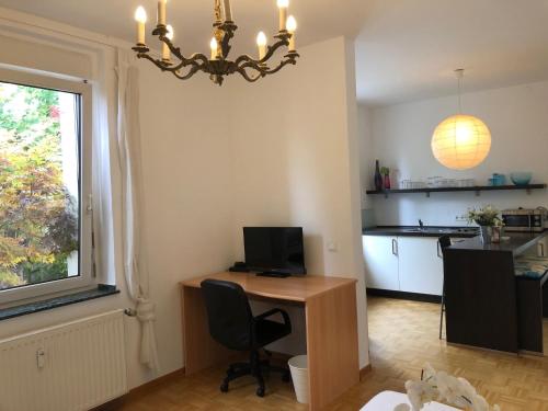 a room with a desk with a computer and a kitchen at studio e - Quiet central business one bedroom apartment for 3 guests in Düsseldorf