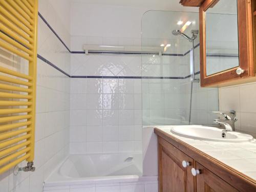 une salle de bain avec une baignoire et un lavabo dans l'établissement Appart au pied des pistes avec piscine, salle de fitness et WiFi - FR-1-455-222, à Aime La Plagne